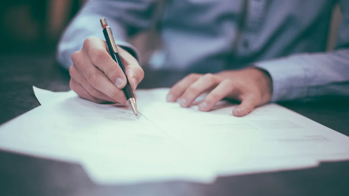 Signature d'un acte authentique chez le notaire, stylo à la main